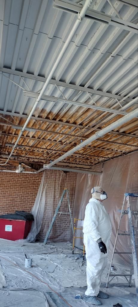 Painter in protective coveralls working on a commercial ceiling