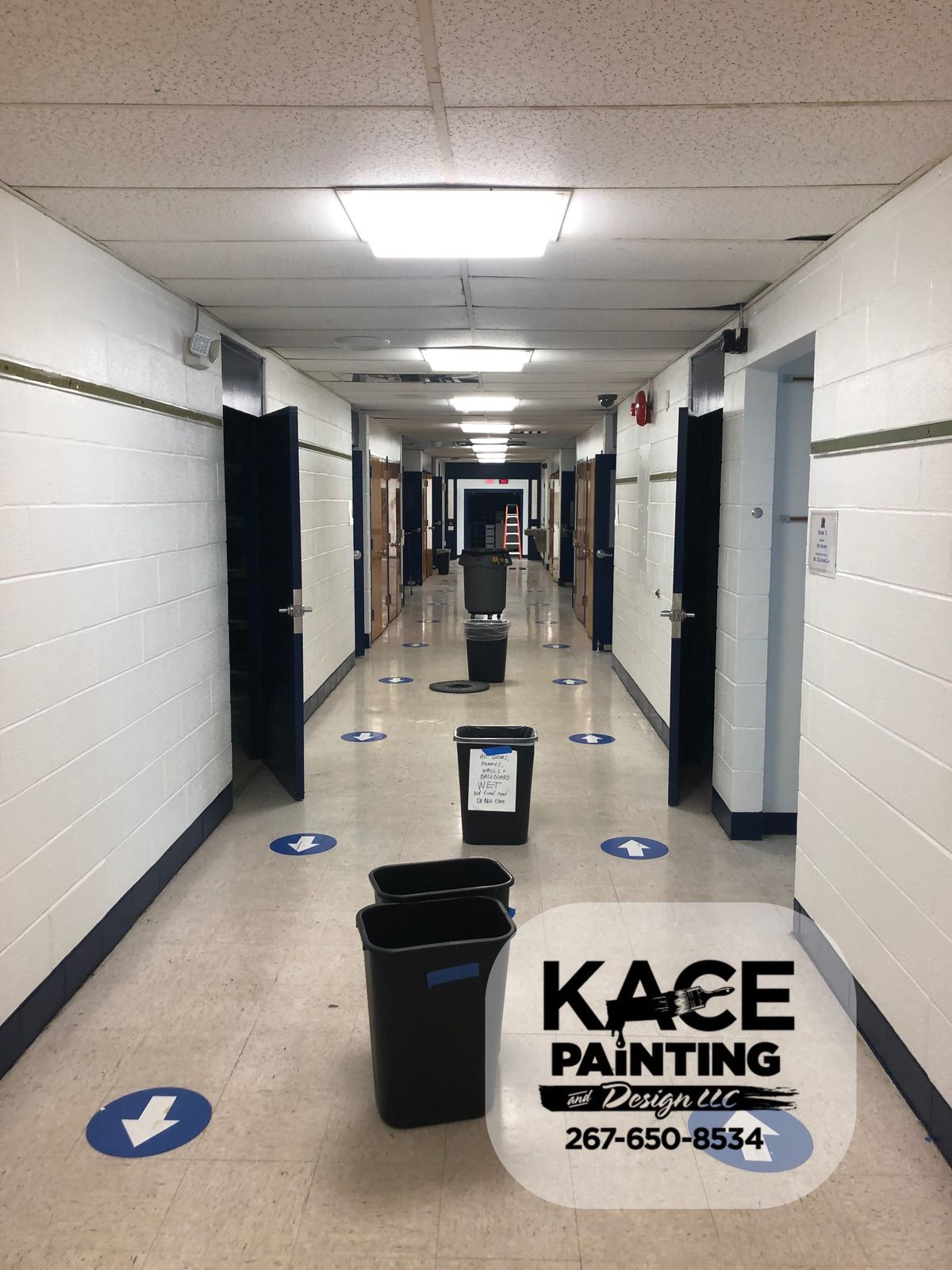 Long commercial corridor with fresh white walls and a dark base