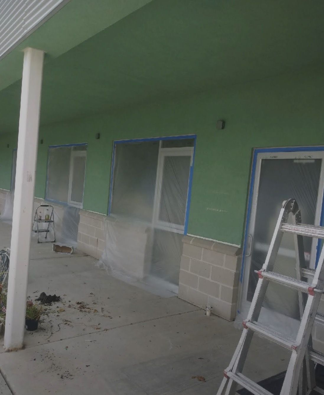 Commercial exterior wall painted sage green, ladder in place