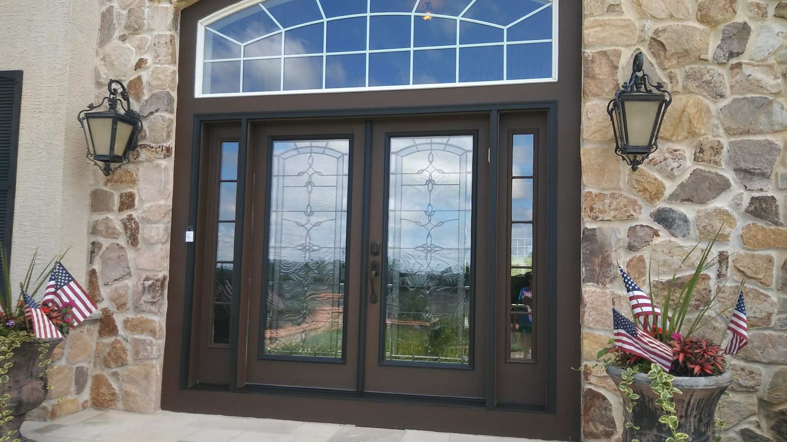 Stone home with an arched transom window and dark painted front doors