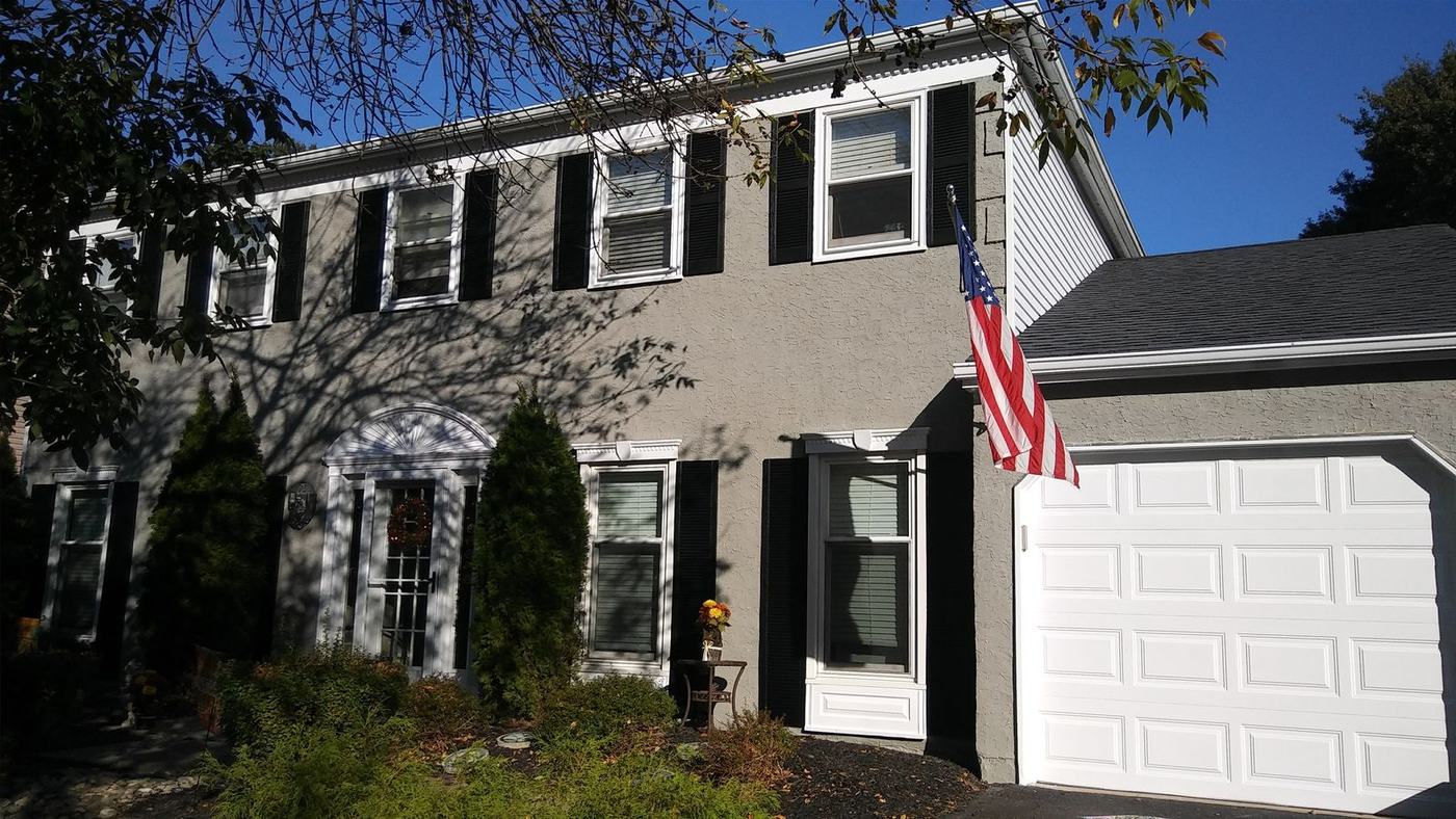 Two story home with black shutters and a white garage door