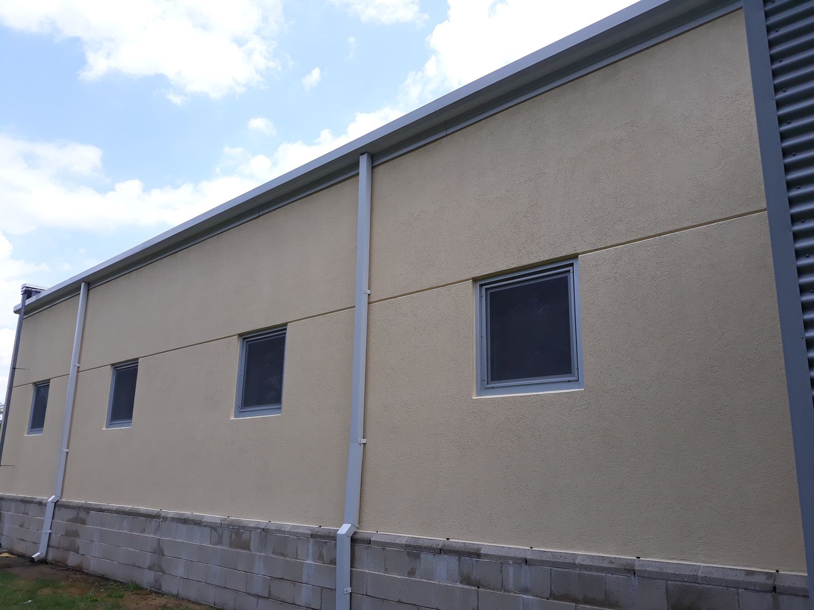 Long exterior wall painted tan above a stone base