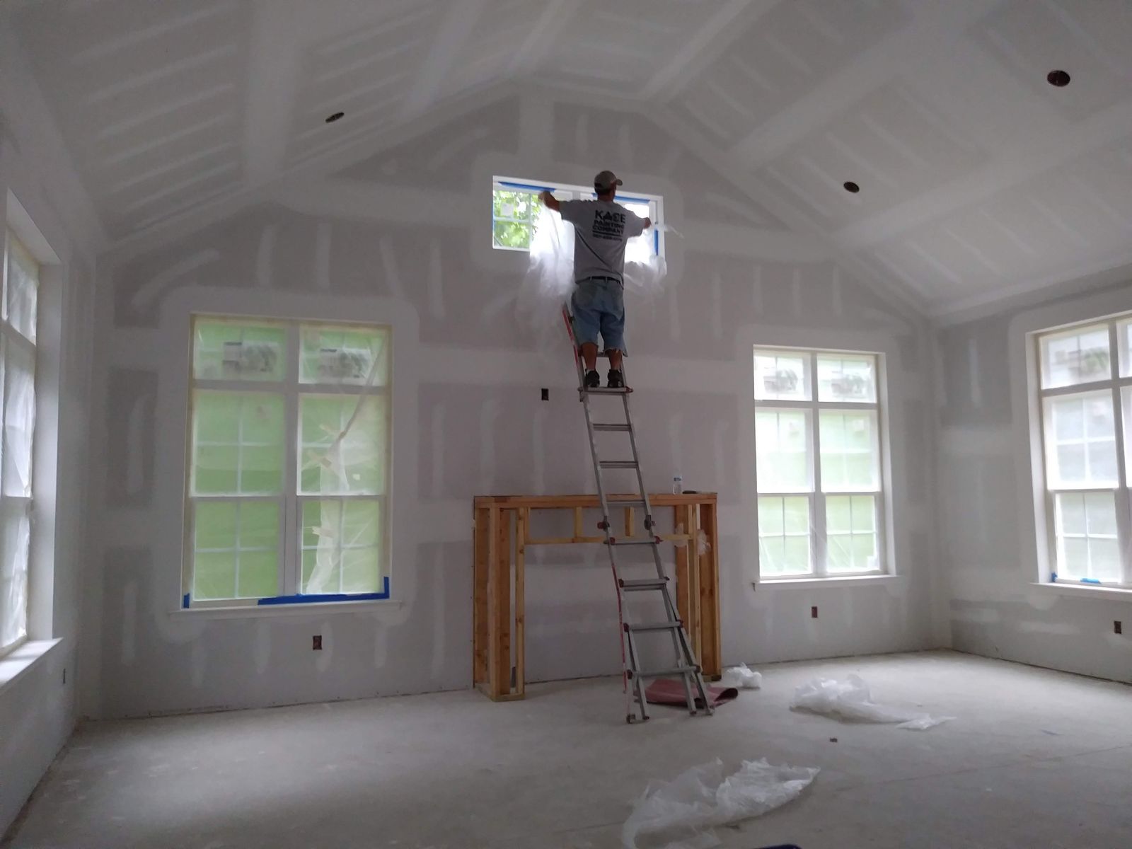 Painter on a ladder prepping a vaulted ceiling before painting