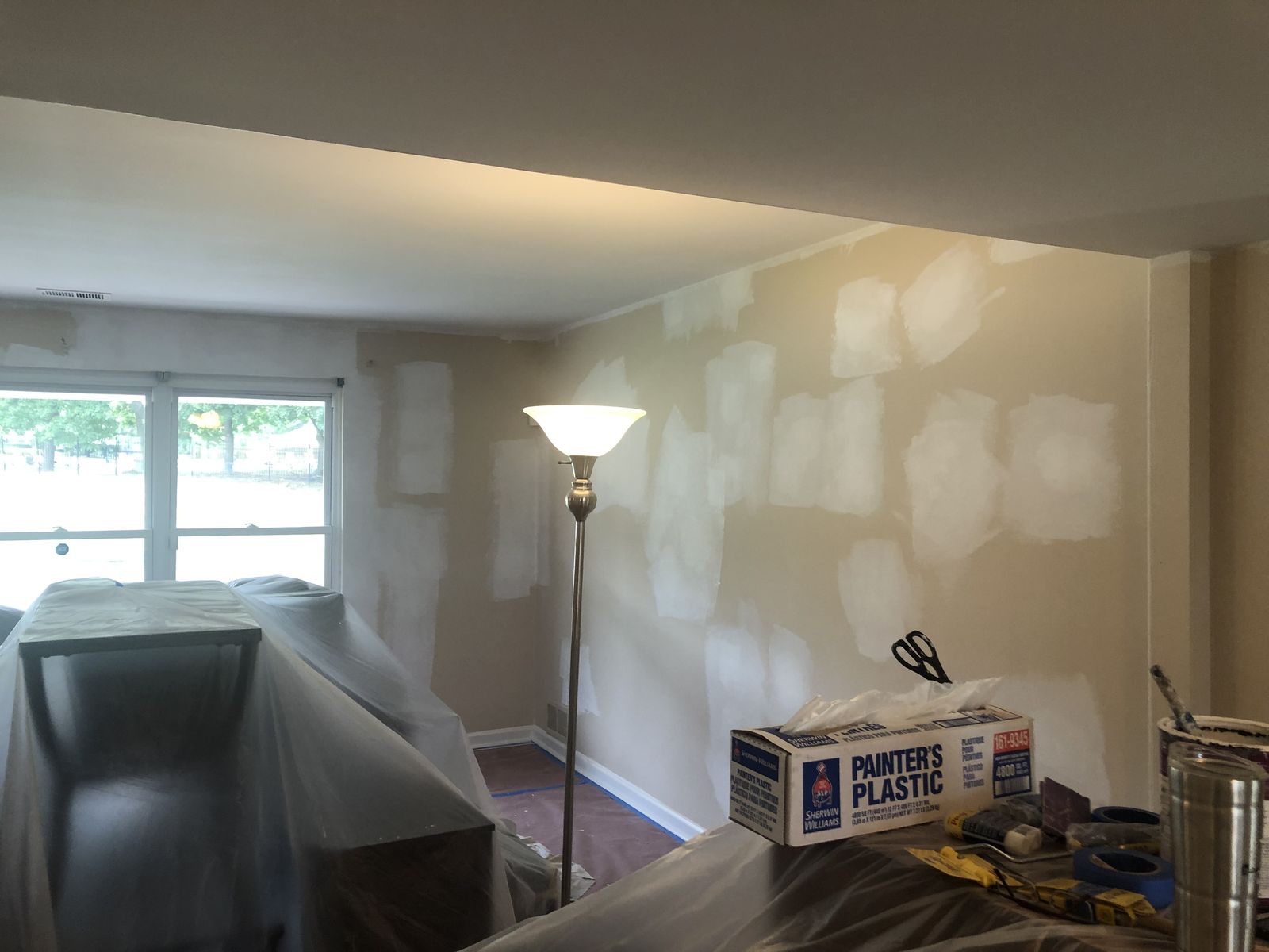 Living room with patched walls ready for primer and furniture covered