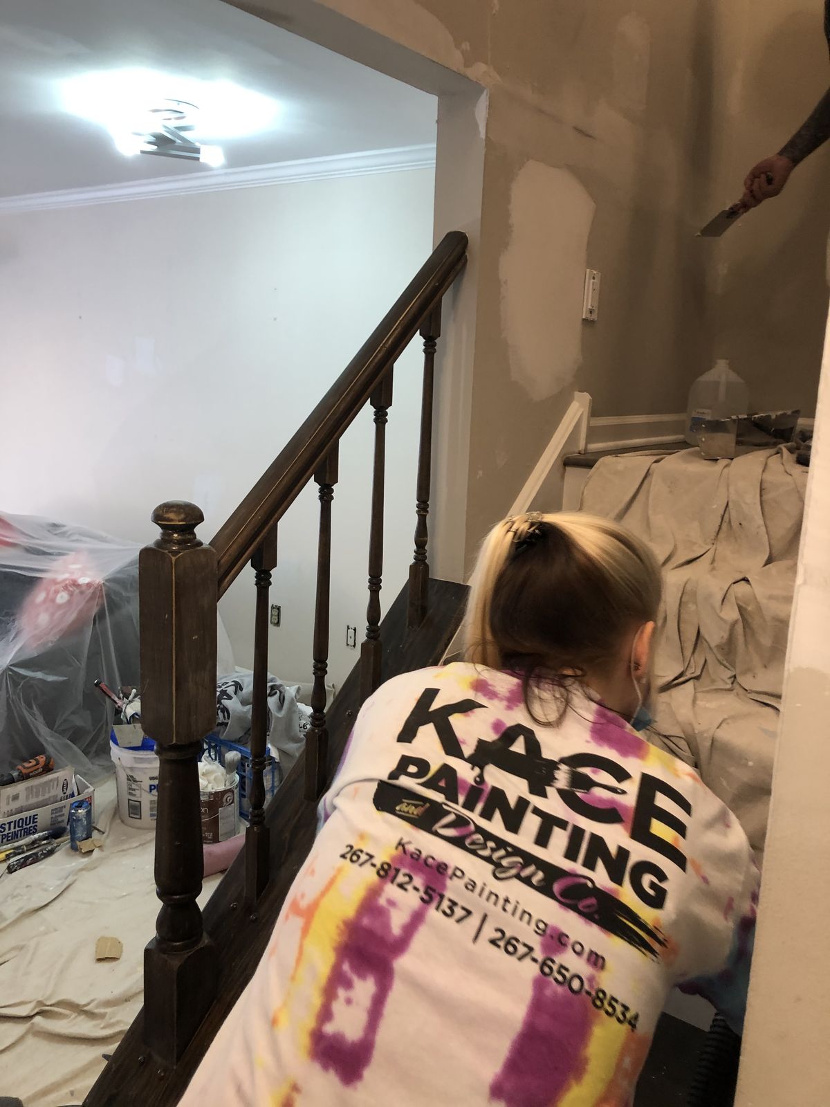 Painter working on a staircase with drop cloths in place