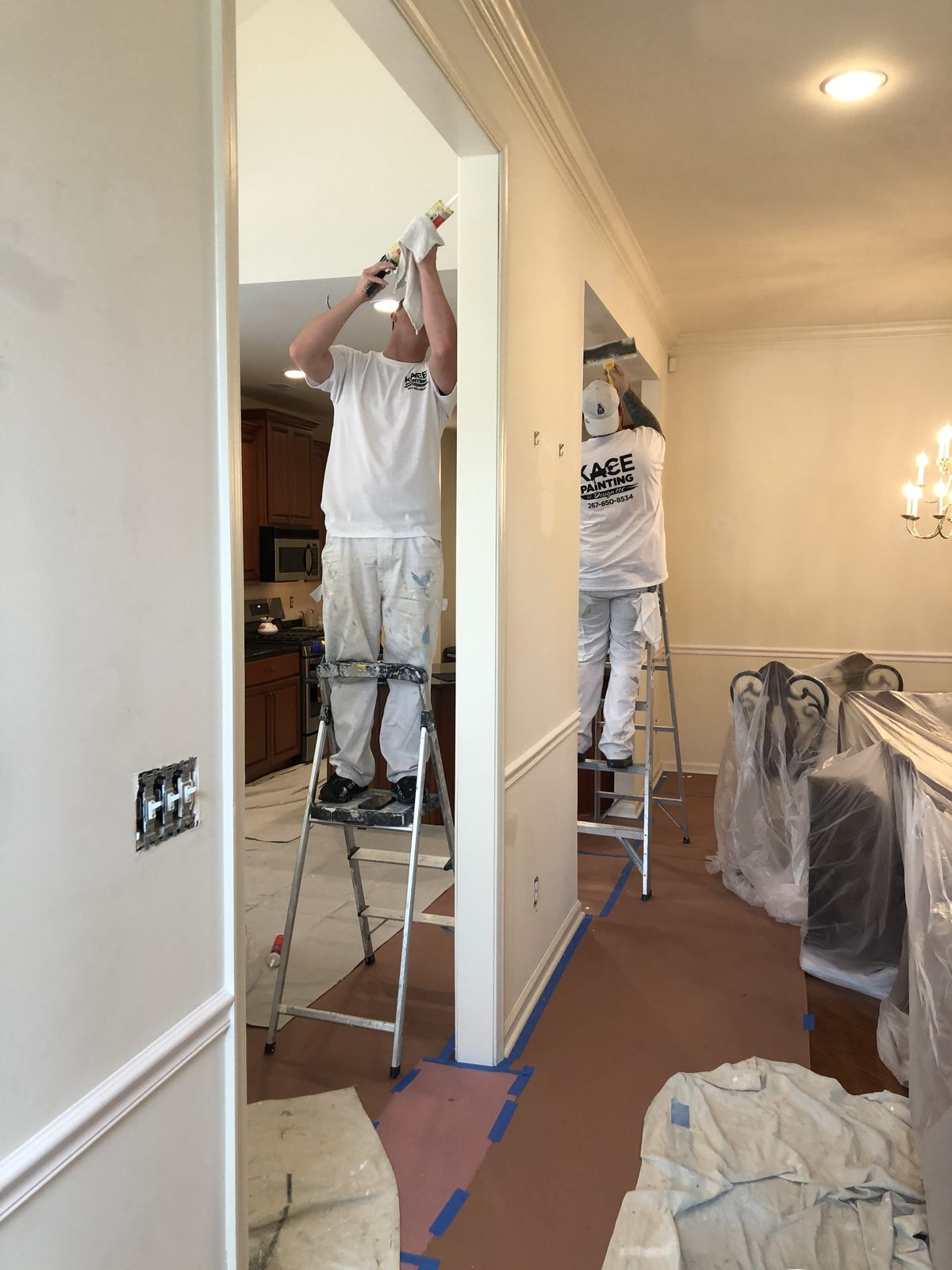 KACE crew painting trim and doors along a hallway