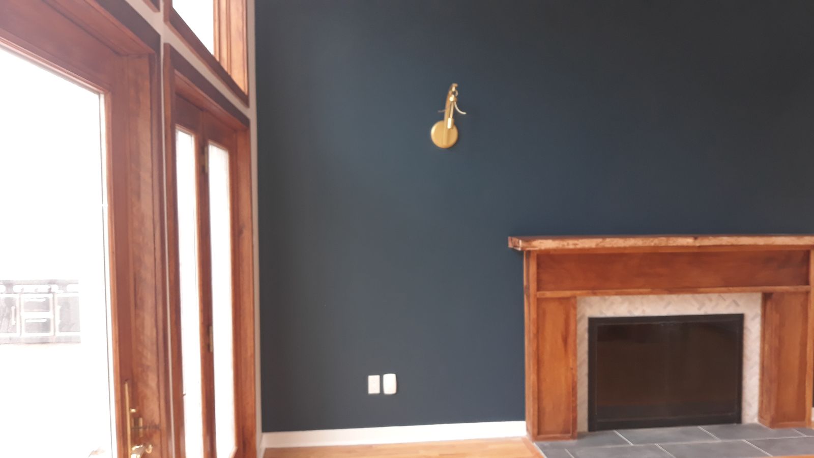 Living room with a deep navy accent wall and wood fireplace mantel
