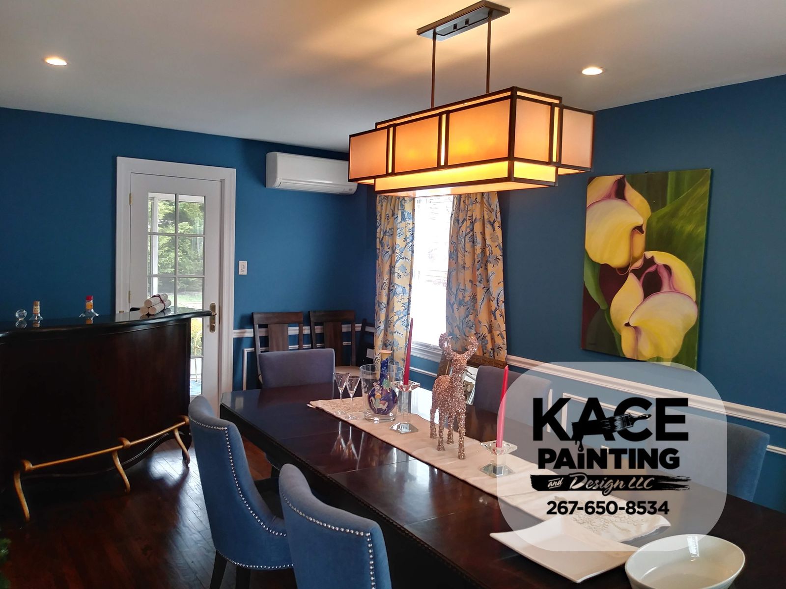 Dining room with deep blue walls and a modern light fixture