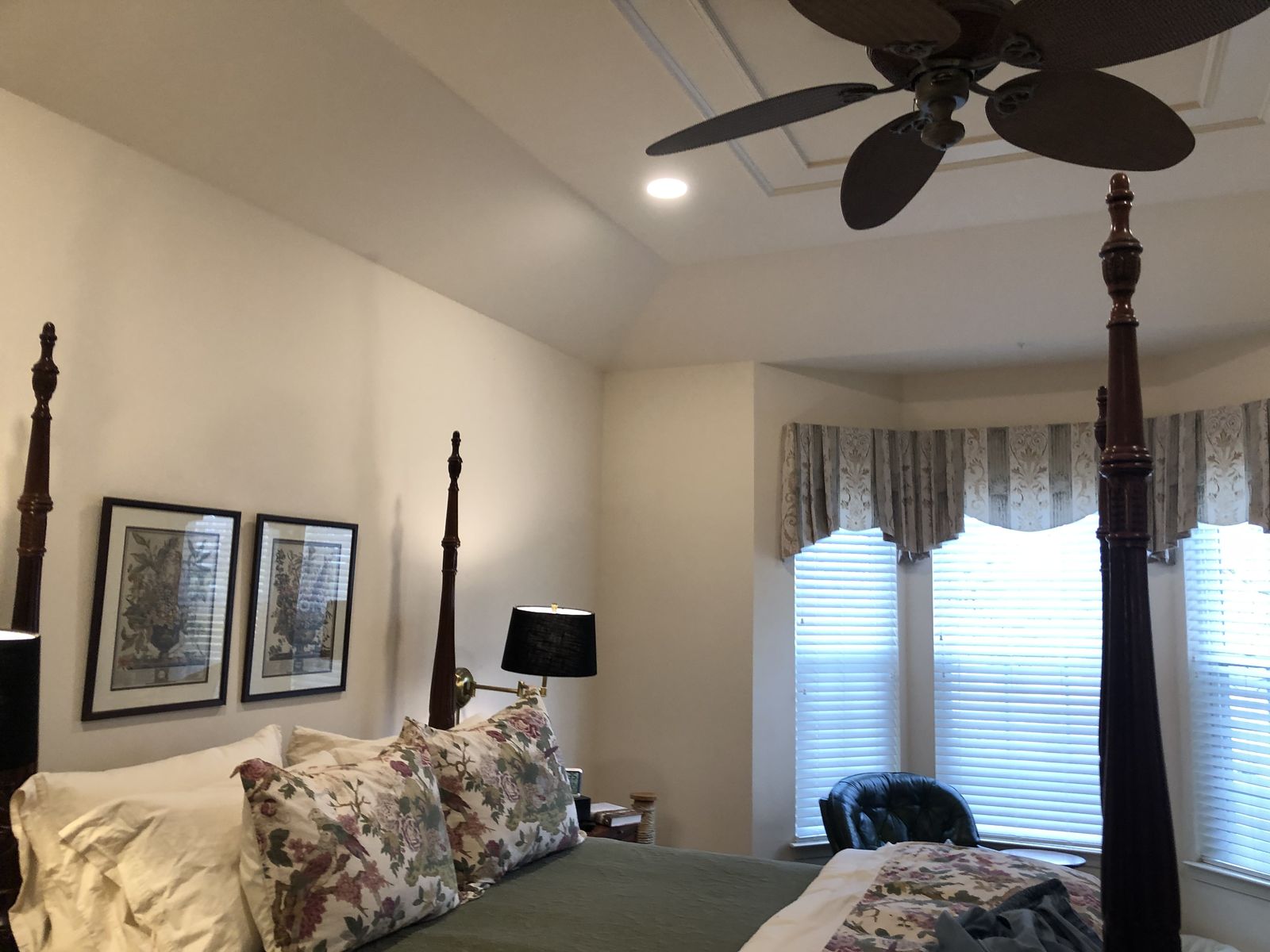 Bedroom with a ceiling fan, neutral walls and framed art