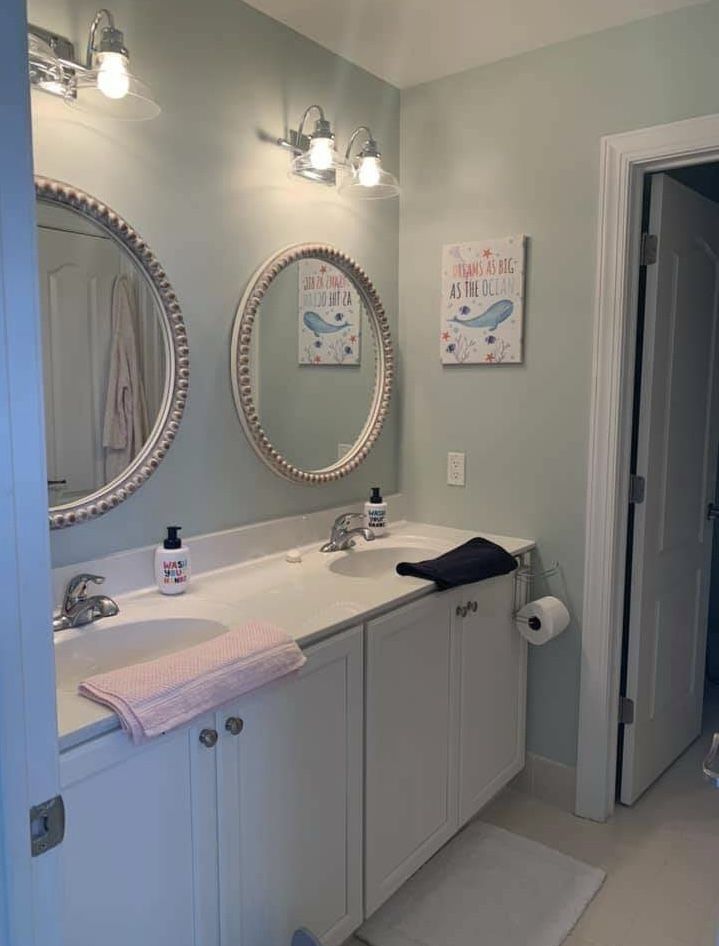 Bathroom vanity with light blue cabinets and a round mirror
