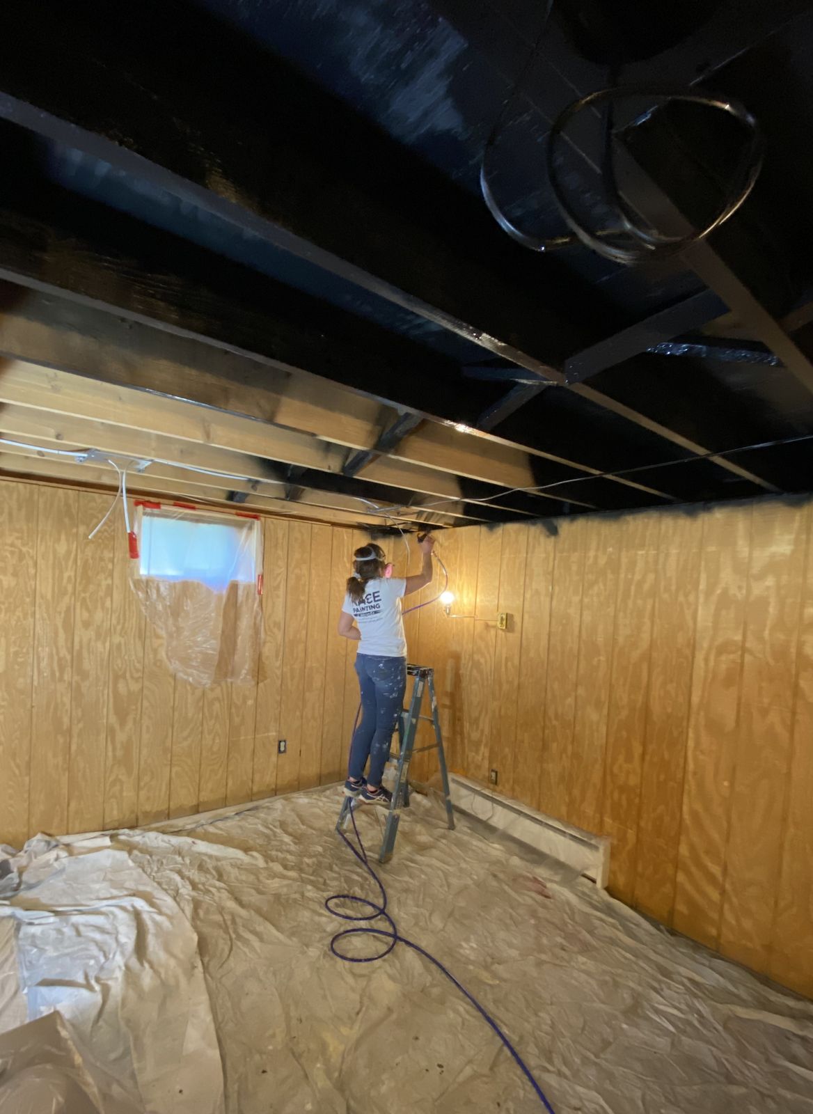 Basement ceiling painted black with exposed joists