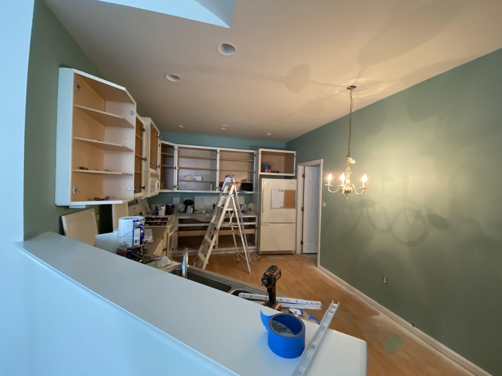 Kitchen with green walls and cabinetry being painted