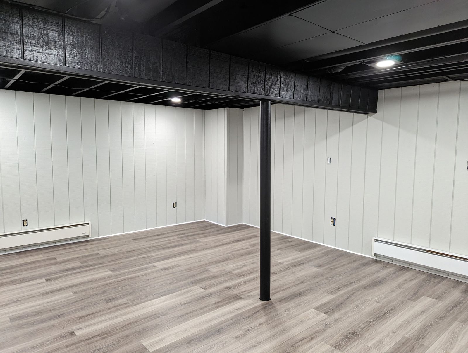 Basement with white shiplap walls and a black painted ceiling