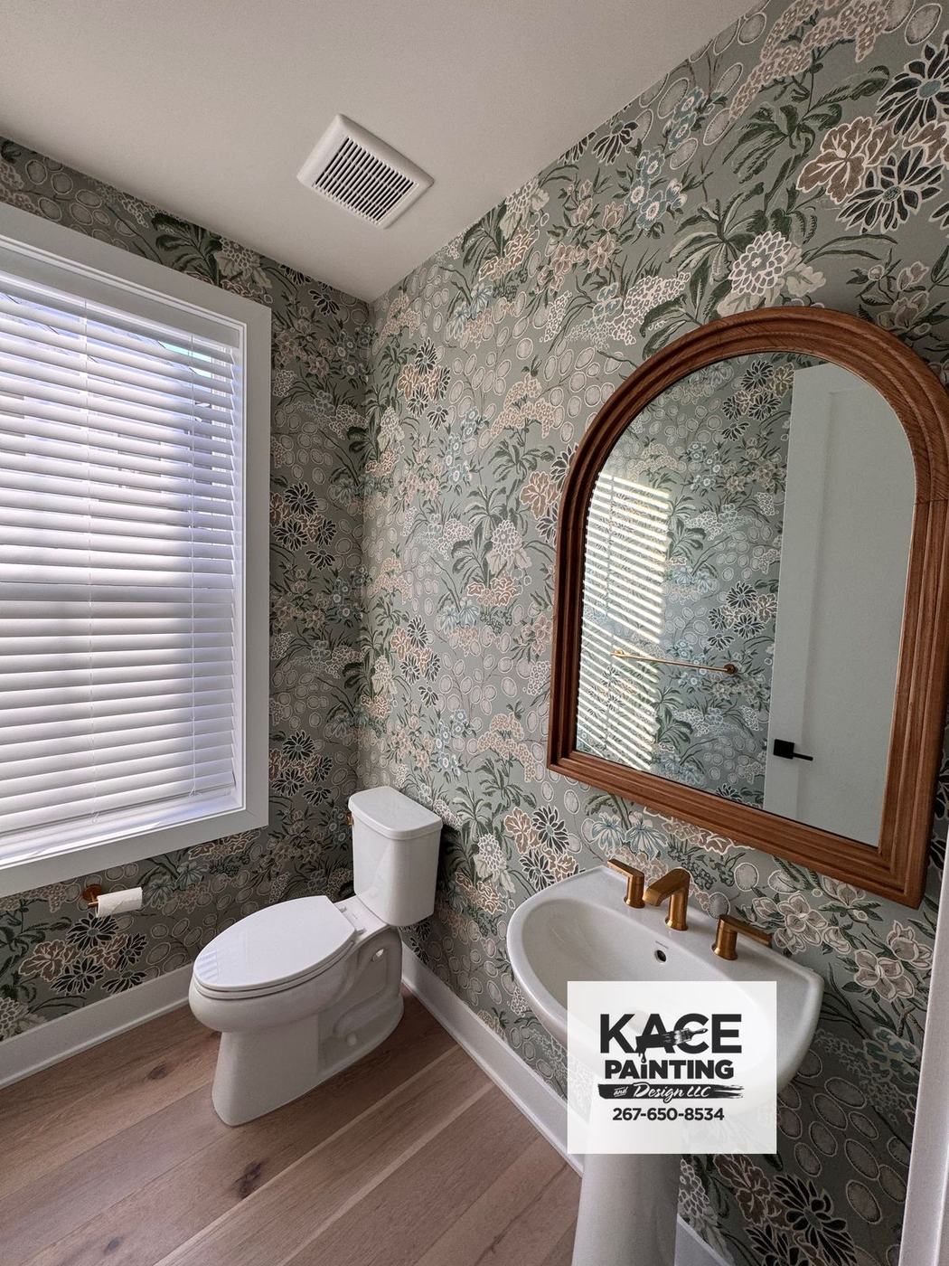 Bathroom with floral wallpaper and an arched wood mirror